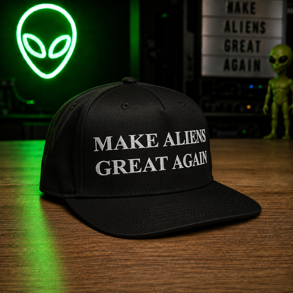 The Official $MAGA Hat — black structured snapback with bold white MAKE ALIENS GREAT AGAIN embroidery, front view on wooden surface with green alien neon sign backdrop